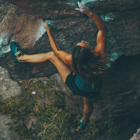Una mujer atlética escala un muro de piedra.