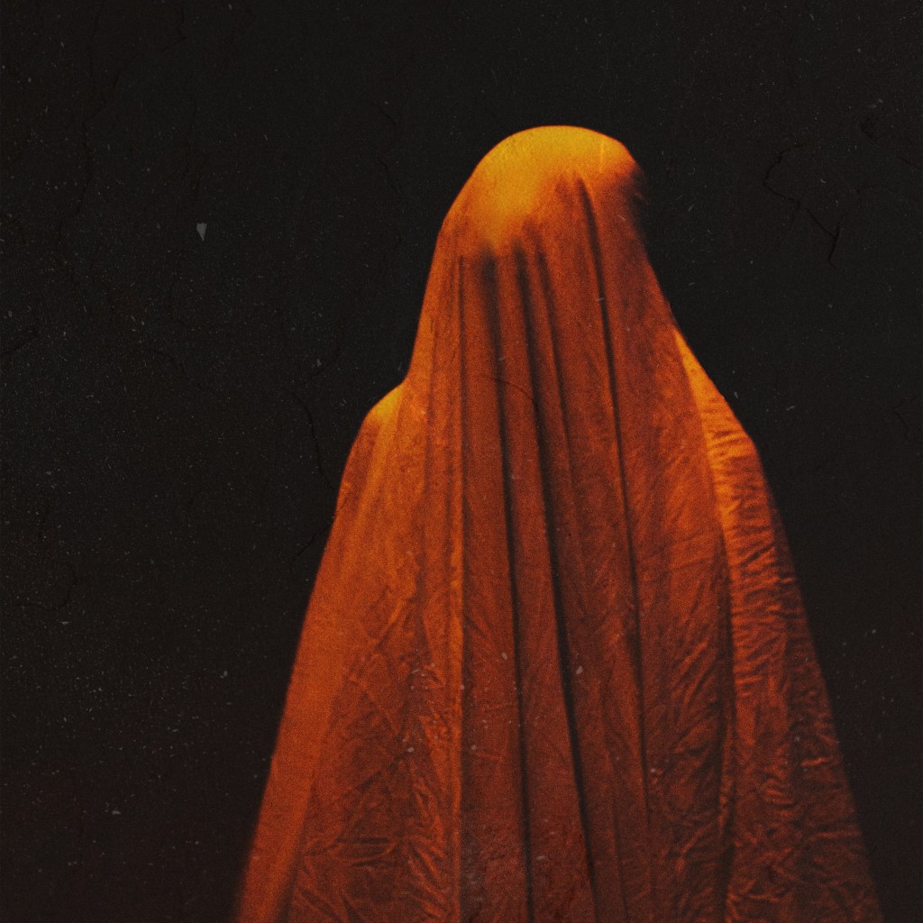 Una forma similar a la de una persona cubierta por una sábana clara. Hay una luz naranja iluminándola.