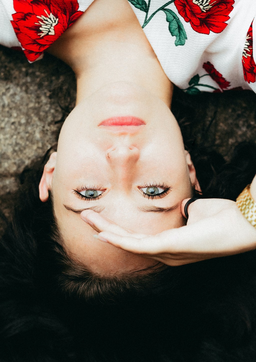 Mujer viendo a la cámara pone su mano izquierda sobre su frente.