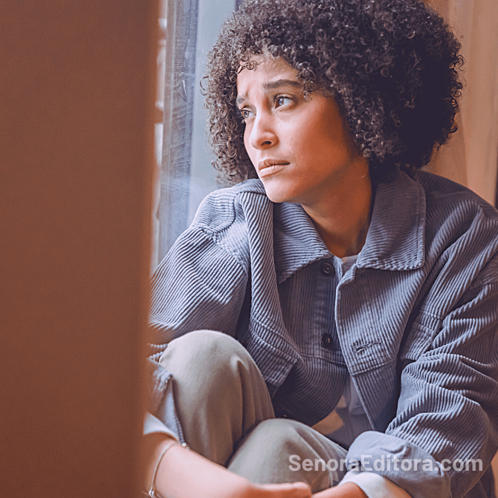 Una mujer mira con desaliento a la ventana.