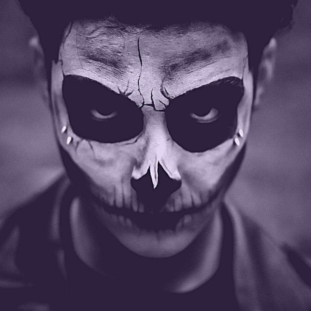 Un hombre con la cara pintada como si fuera una calavera mira directamente a la cámara.