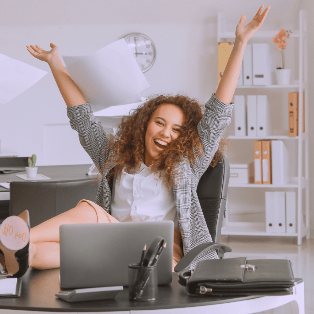 Mujer levanta los brazos aventando papeles al aire en pose celebratoria.